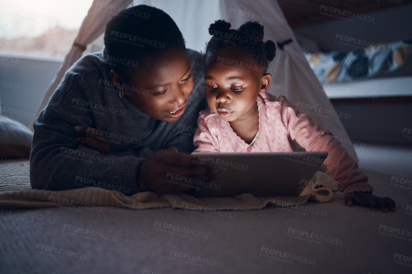 Buy stock photo Shot of a mother reading bedtime stories with her daughter on a digital tablet