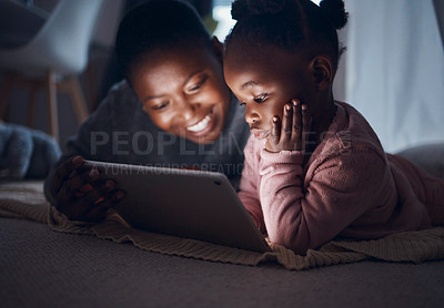 Buy stock photo Shot of a mother reading bedtime stories with her daughter on a digital tablet