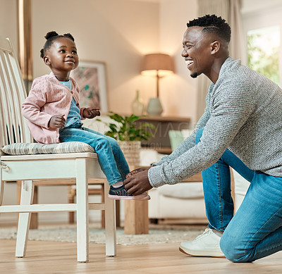 Buy stock photo Cropped shot of a handsome young man helping his daughter tie her shoelaces in the living room at home