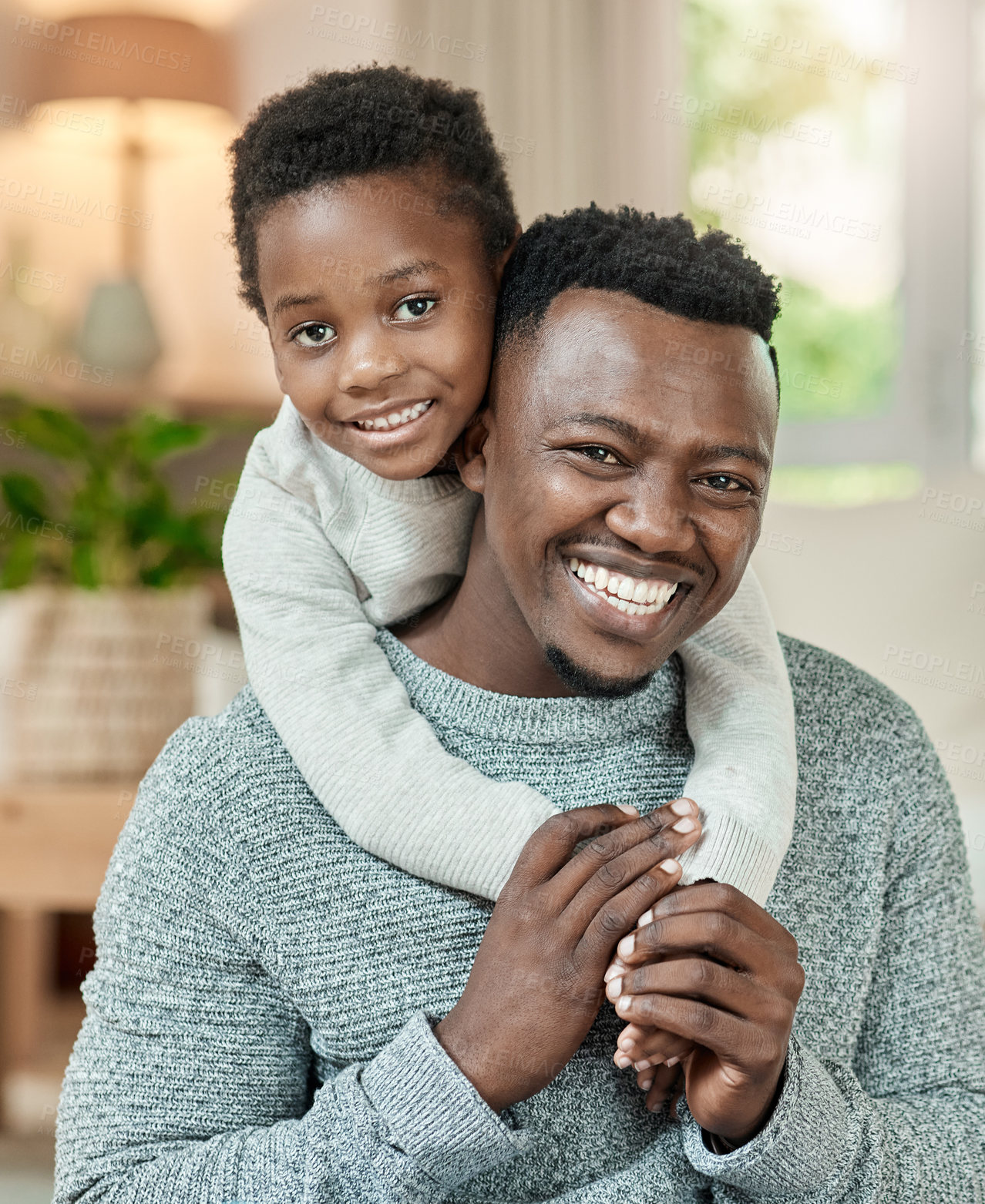 Buy stock photo Cropped portrait of a handsome young man piggybacking his son in the living room at home