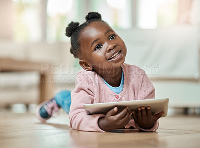 Buy stock photo Full length shot of an adorable little girl using a tablet while lying on the living room floor at home