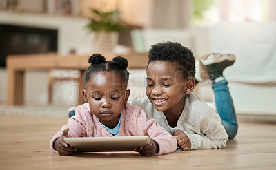 Buy stock photo Full length shot of young boy and his adorable little sister using a tablet while lying on the living room floor at home
