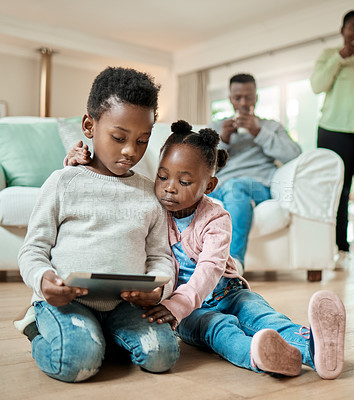 Buy stock photo Full length shot of young boy and his adorable little sister using a tablet while sitting on the living room floor at home
