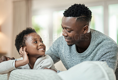 Buy stock photo Cropped shot of an adorable little boy and his father relaxing on a sofa in their living room at home