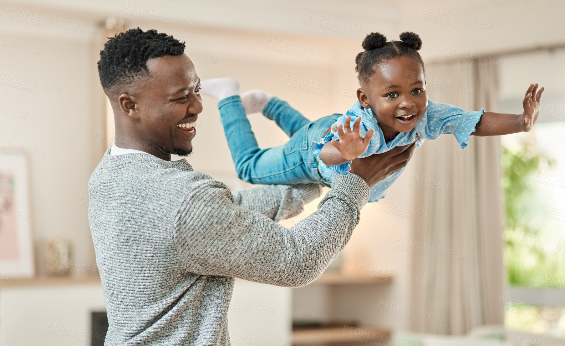 Buy stock photo Cropped shot of a handsome young man lifting is daughter high up in the air while playing in the living room at home