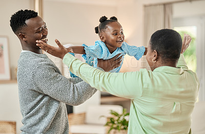 Buy stock photo Cropped shot of a handsome young man lifting is daughter high up in the air while playing in the living room at home while mom watches on