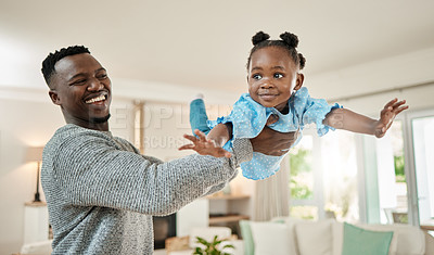 Buy stock photo Cropped shot of a handsome young man lifting is daughter high up in the air while playing in the living room at home