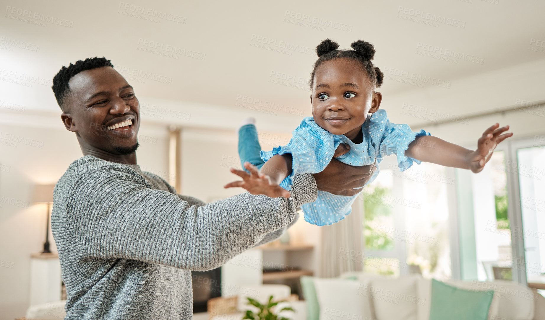 Buy stock photo Cropped shot of a handsome young man lifting is daughter high up in the air while playing in the living room at home