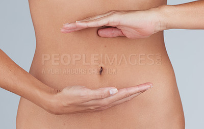 Buy stock photo Cropped shot of an unrecognizable woman standing alone in the studio and showing her tummy