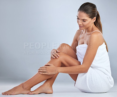 Buy stock photo Full length shot of an attractive young woman sitting alone and posing in her towel in the studio