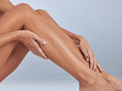 Buy stock photo Cropped shot of an unrecognizable woman sitting alone and touching her legs in the studio