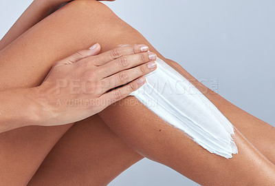 Buy stock photo Cropped shot of an unrecognizable woman sitting alone and applying shaving cream to her legs in the studio
