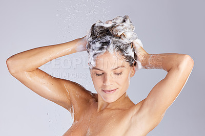 Buy stock photo Studio shot of an attractive young woman washing her hair while taking a shower against a grey background