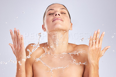 Buy stock photo Studio shot of an attractive young woman washing her face against a grey background