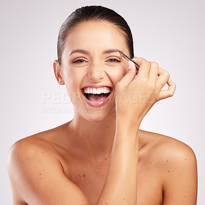 Buy stock photo Shot of an attractive young woman plucking her eyebrows against a studio background
