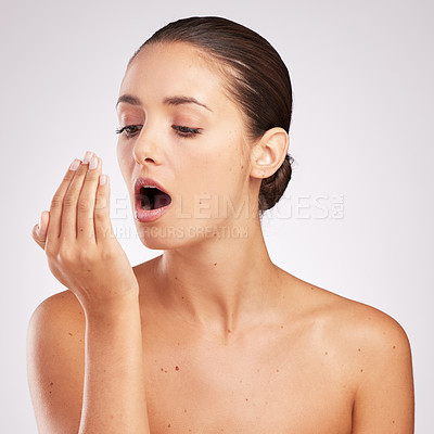 Buy stock photo Shot of an attractive young woman smelling her breath against a studio background