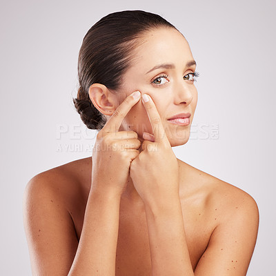 Buy stock photo Shot of an attractive young woman touching her face and looking unhappy against a studio background