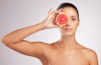Buy stock photo Shot of an attractive young woman holding a grapefruit against a studio background