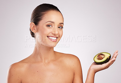 Buy stock photo Shot of an attractive young woman holding an avocado against a studio background