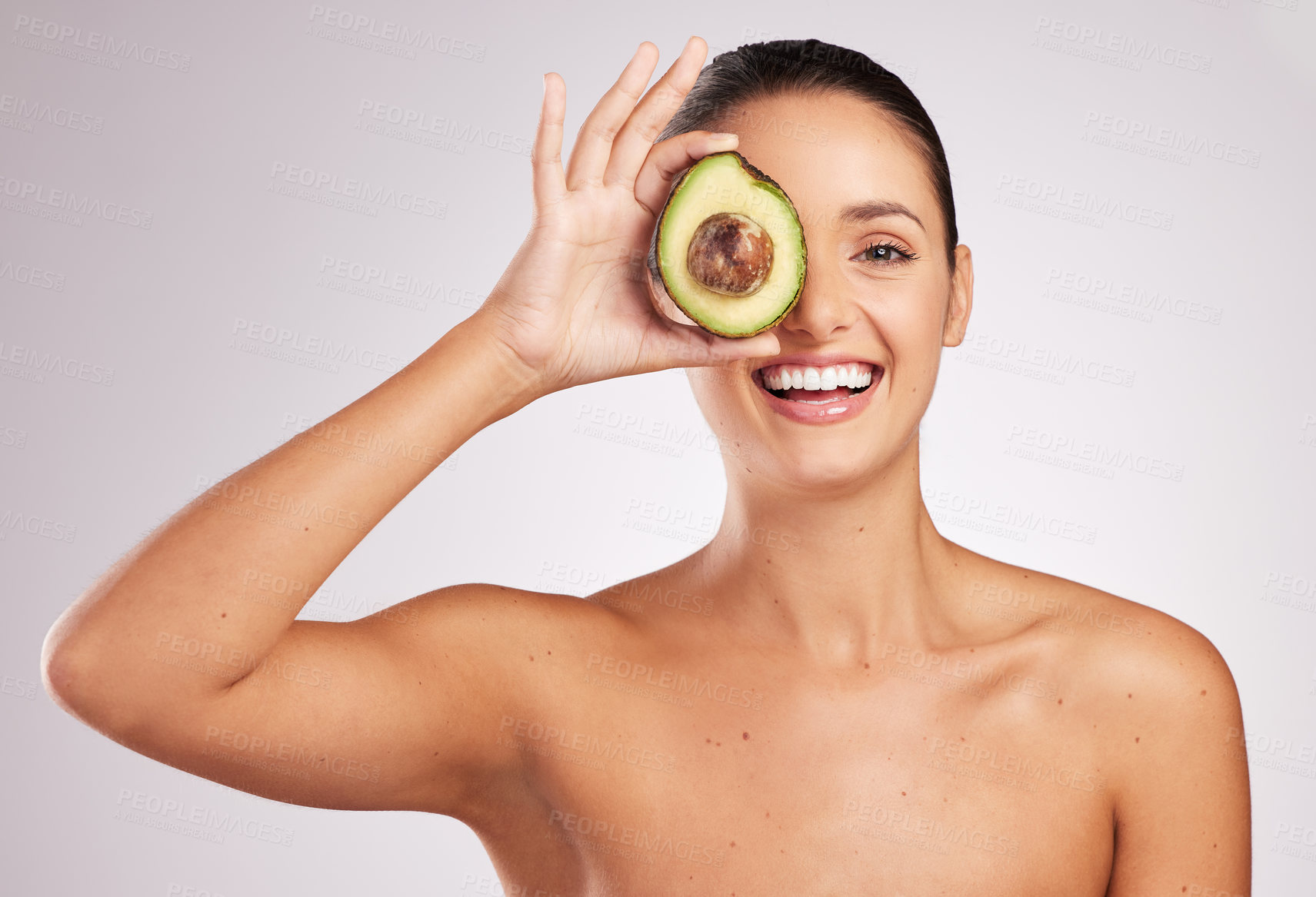 Buy stock photo Shot of an attractive young woman holding an avocado against a studio background