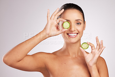 Buy stock photo Shot of an attractive young woman holding a cucumber slice against a studio background