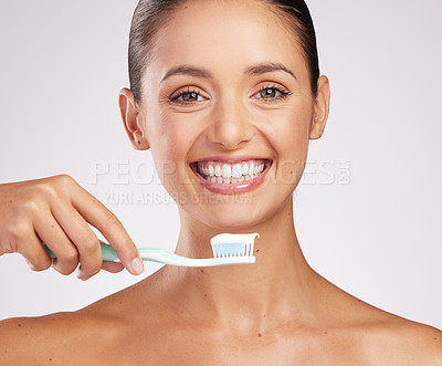 Buy stock photo Shot of an attractive young woman brushing her teeth against a studio background
