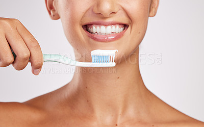 Buy stock photo Shot of an attractive young woman brushing her teeth against a studio background