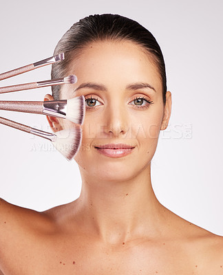 Buy stock photo Shot of an attractive young woman holding a set of makeup brushes against a studio background