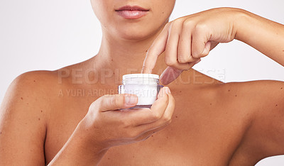 Buy stock photo Shot of an attractive young woman applying moisturiser to her face against a studio background