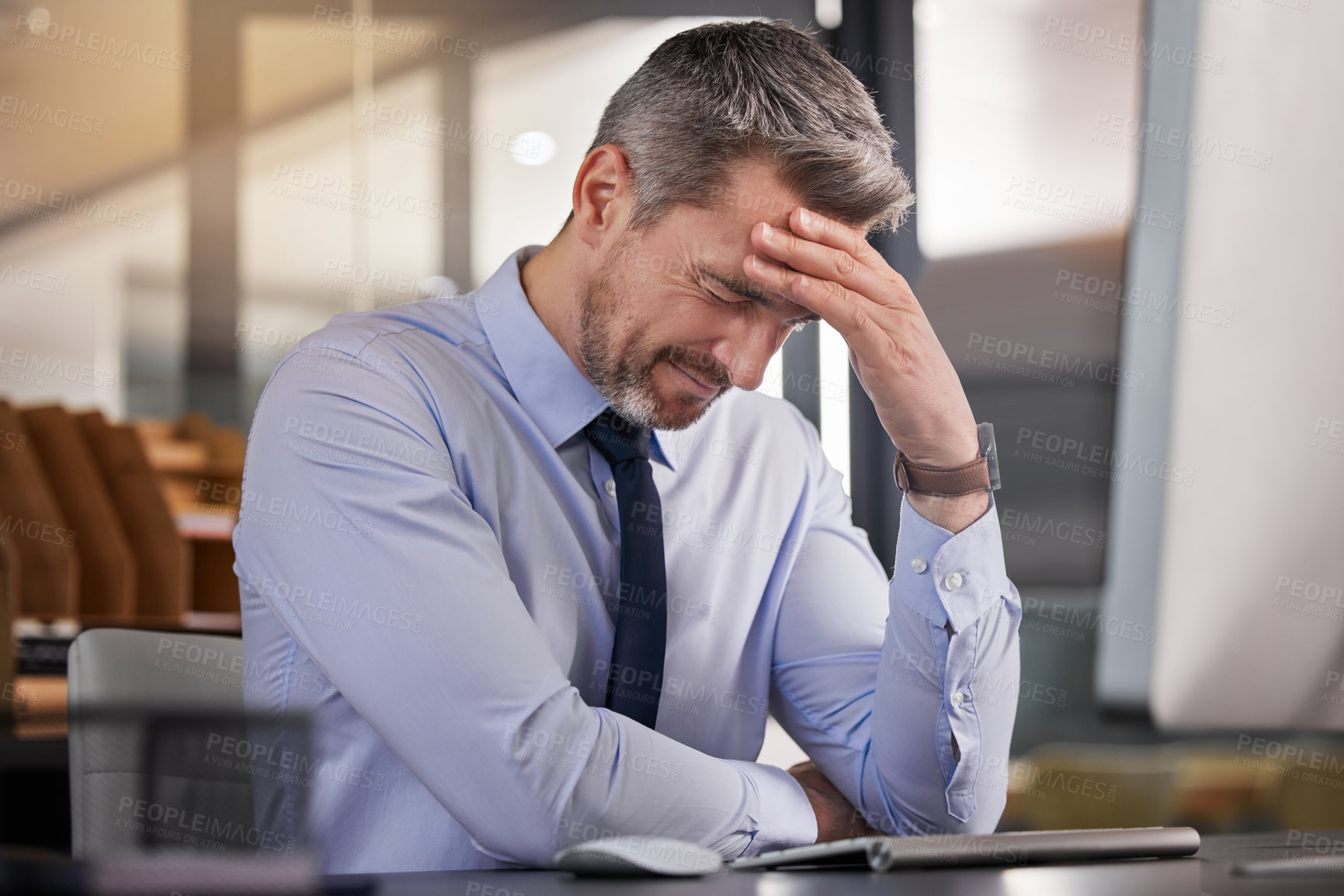 Buy stock photo Shot of a businessman suffering from a headache while sitting at his desk