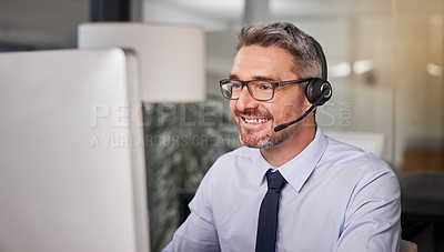 Buy stock photo Shot of a call centre agent wearing a headset while working on his computer