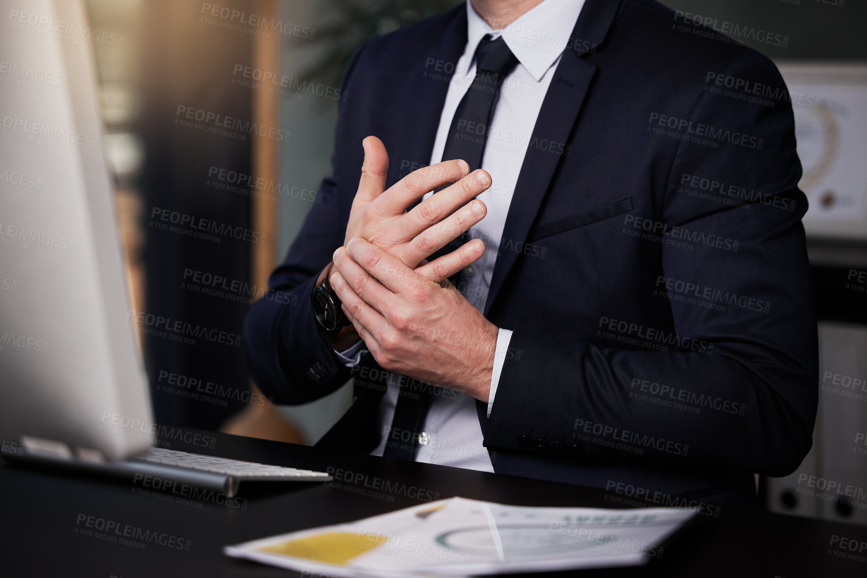 Buy stock photo Shot of a businessman experiencing discomfort in his hands while working at his desk
