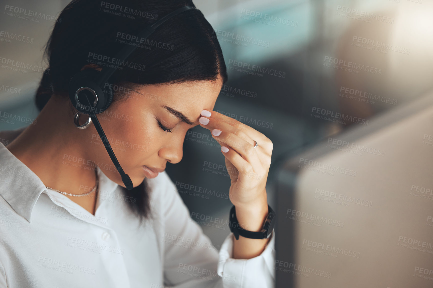 Buy stock photo Shot of a young call centre agent sitting alone in her office and feeling stressed