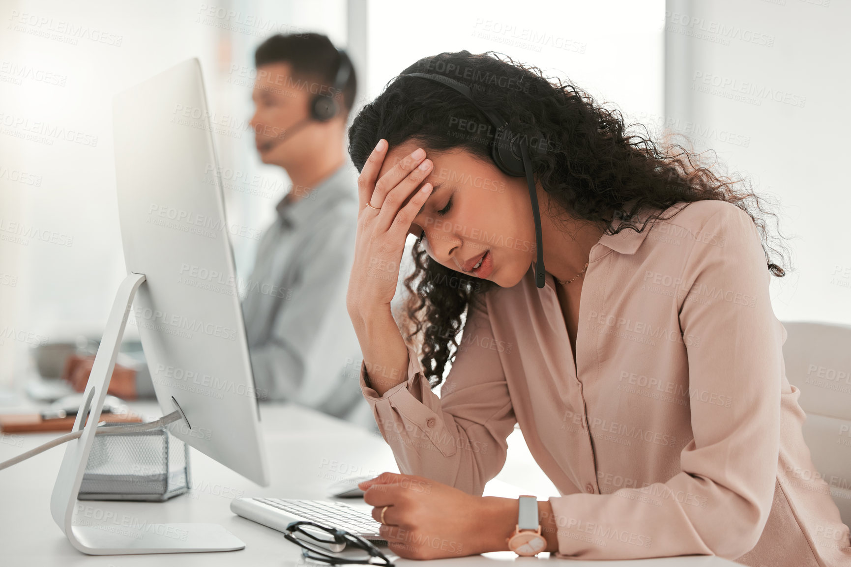 Buy stock photo Shot of a young female call center agent suffering from a headache in an office at work