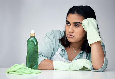 Buy stock photo Shot of a young woman looking angry while cleaning