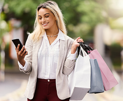 Buy stock photo Cropped shot of an attractive young woman texting while out shopping in the city
