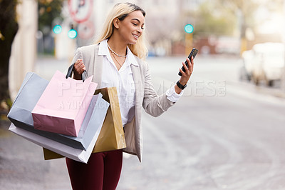 Buy stock photo Cropped shot of an attractive young woman checking her cellphone to see whereabout her cab is while out shopping in the city