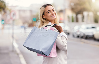 Buy stock photo Rearview portrait of an attractive young woman walking with her bags over her shoulder while out shopping in the city