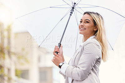 Buy stock photo Cropped shot of an attractive young businesswoman walking through the city with an umbrella