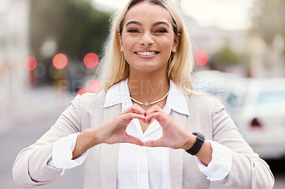 Buy stock photo Cropped portrait of an attractive young businesswoman making a heart shape with her hands while walking through the city