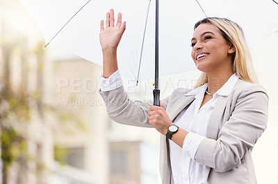 Buy stock photo Cropped shot of an attractive young businesswoman waving while walking through the city with an umbrella