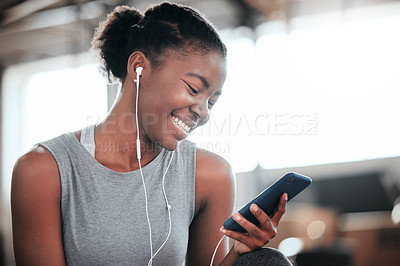 Buy stock photo Shot of a young beautiful woman using her cellphone and earphones at the gym