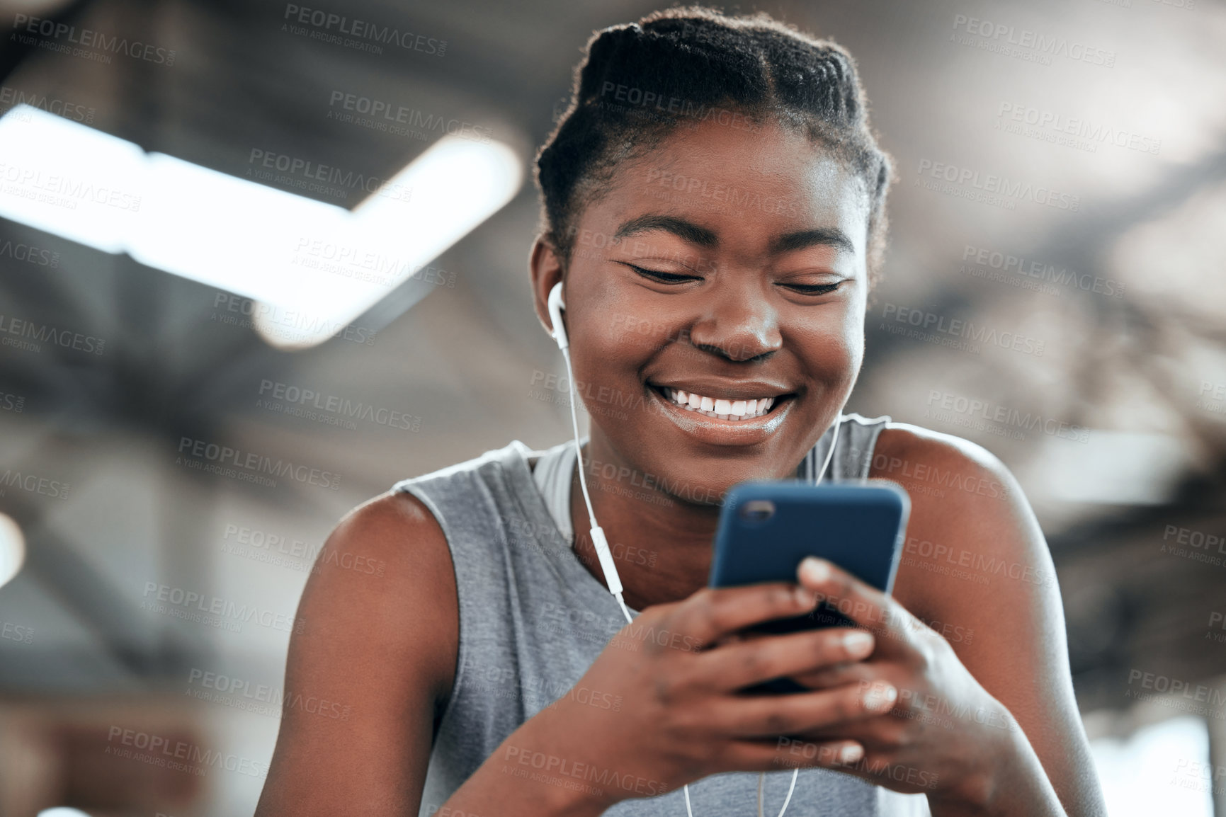 Buy stock photo Phone, earphones and happy black woman in gym for fitness, sports or exercise. Smartphone, music and African female athlete on social media break, internet and web texting after workout or training.