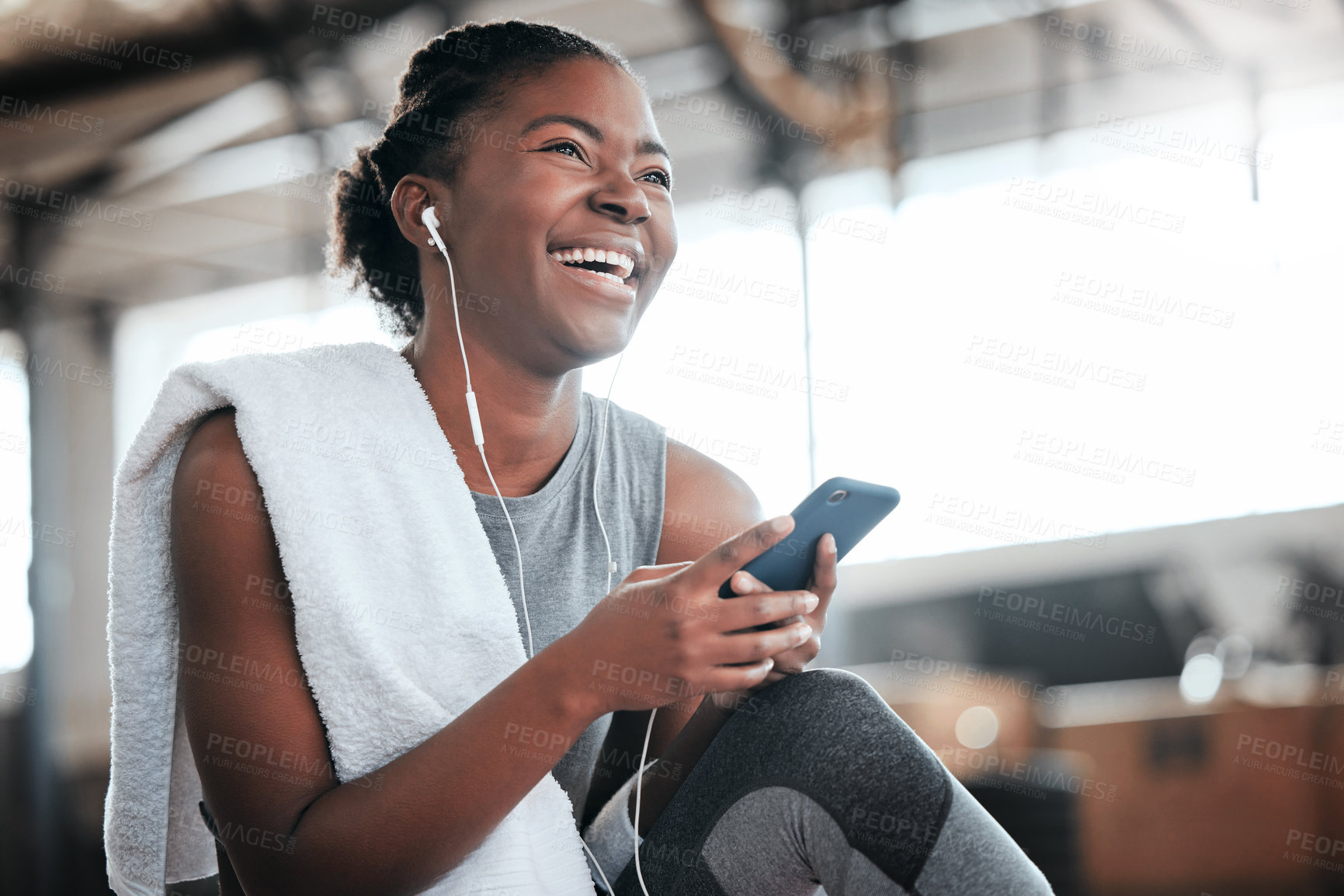 Buy stock photo Earphones, smartphone and laughing black woman in gym for fitness, sports or exercise. Phone, music or African female athlete laugh at funny meme or comedy on break after workout, training or pilates