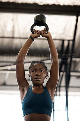 Buy stock photo Low angle shot of an attractive and athletic young woman working out with a kettle bell in the gym