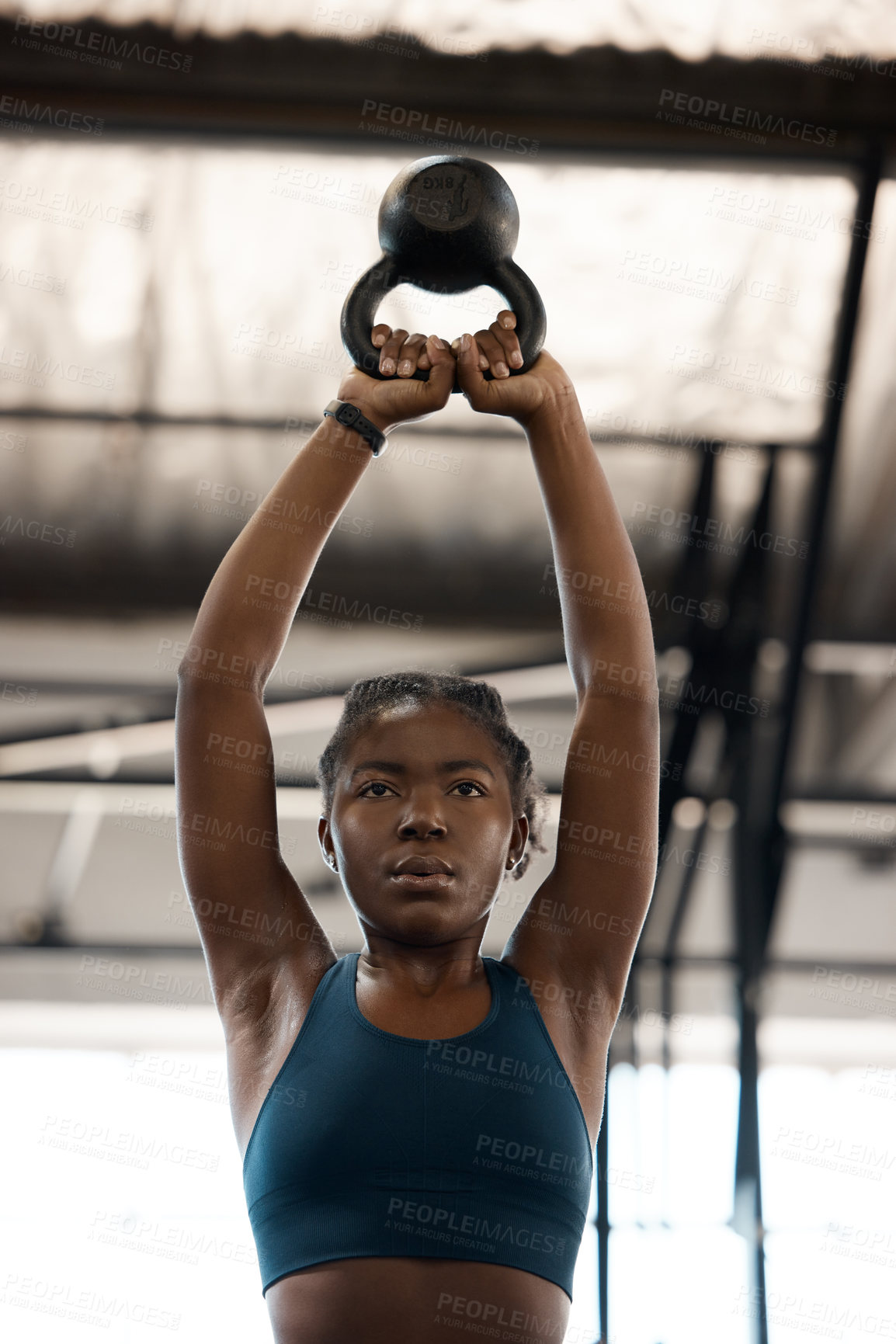 Buy stock photo Low angle shot of an attractive and athletic young woman working out with a kettle bell in the gym