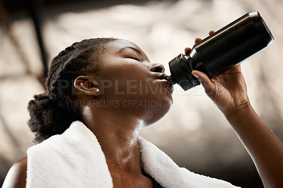 Buy stock photo Low angle shot of an attractive and athletic young woman drinking water during her workout in the gym