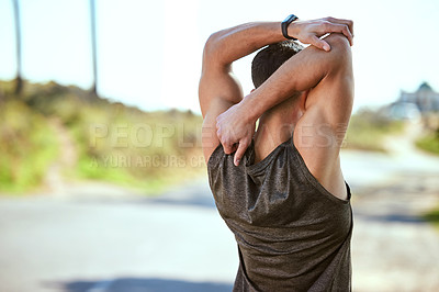 Buy stock photo Rearview shot of a sporty young man stretching his arms while exercising outdoors