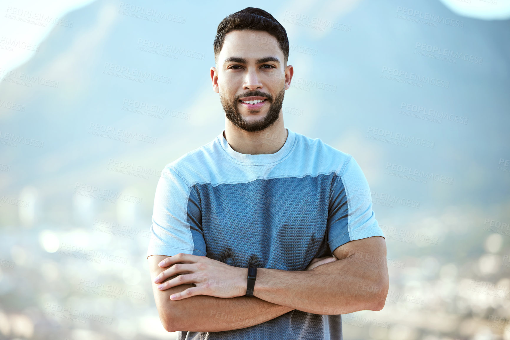 Buy stock photo Portrait of a sporty young man standing with his arms crossed while exercising outdoors