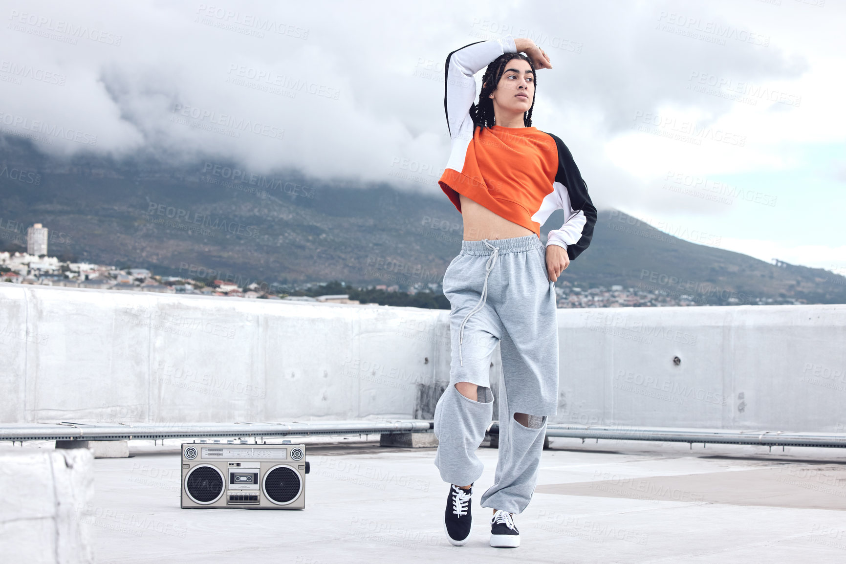 Buy stock photo Shot of a young woman out on a rooftop with a boombox